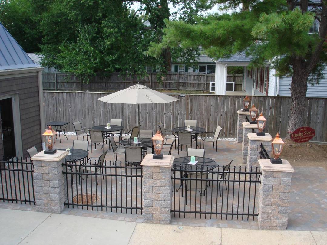 Outdoor dining patio at Old Towne Pub with stone pillars, iron fencing, and lanterns
