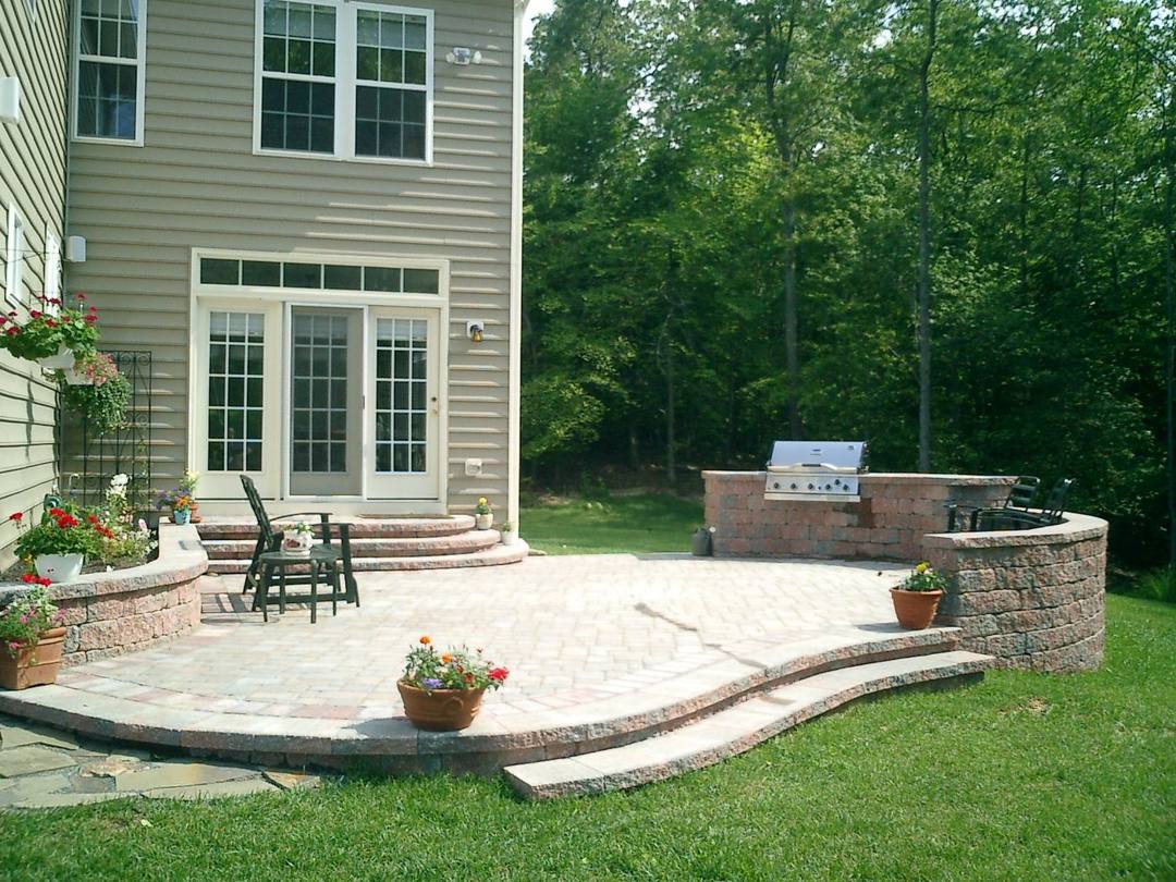 Curved raised paver patio with a grill station and seat wall