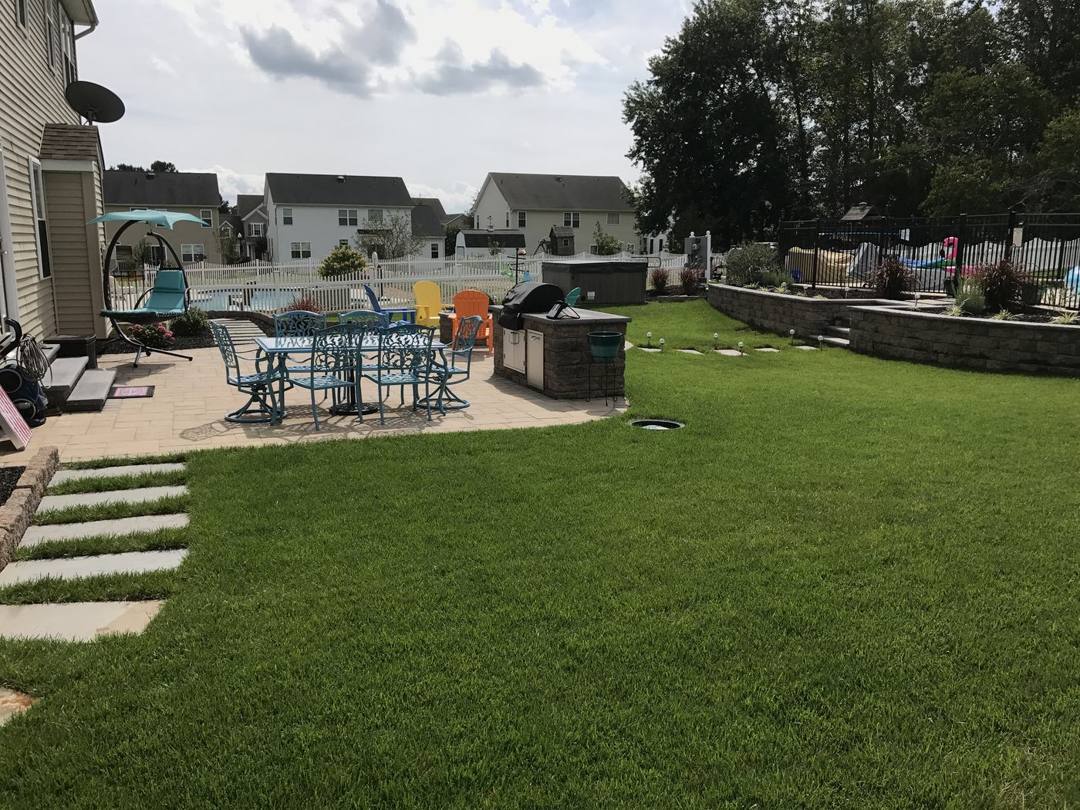 Backyard paver patio with a dining set and outdoor kitchen