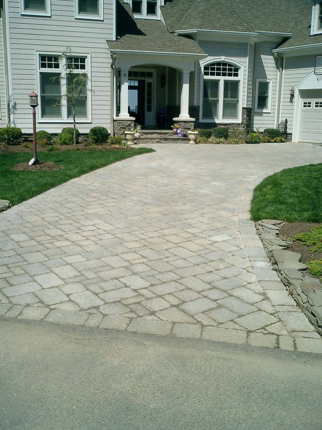 Curved gray paver driveway in front of a home