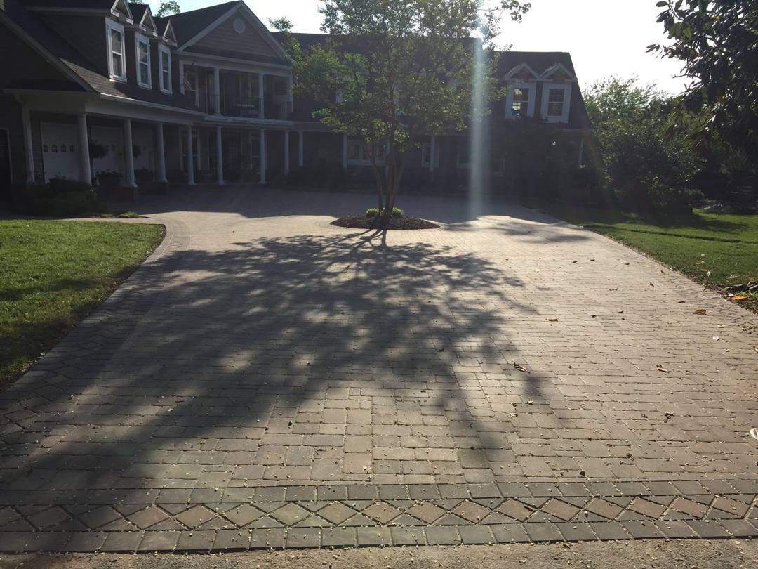 Wide paver driveway with a decorative border in front of a home