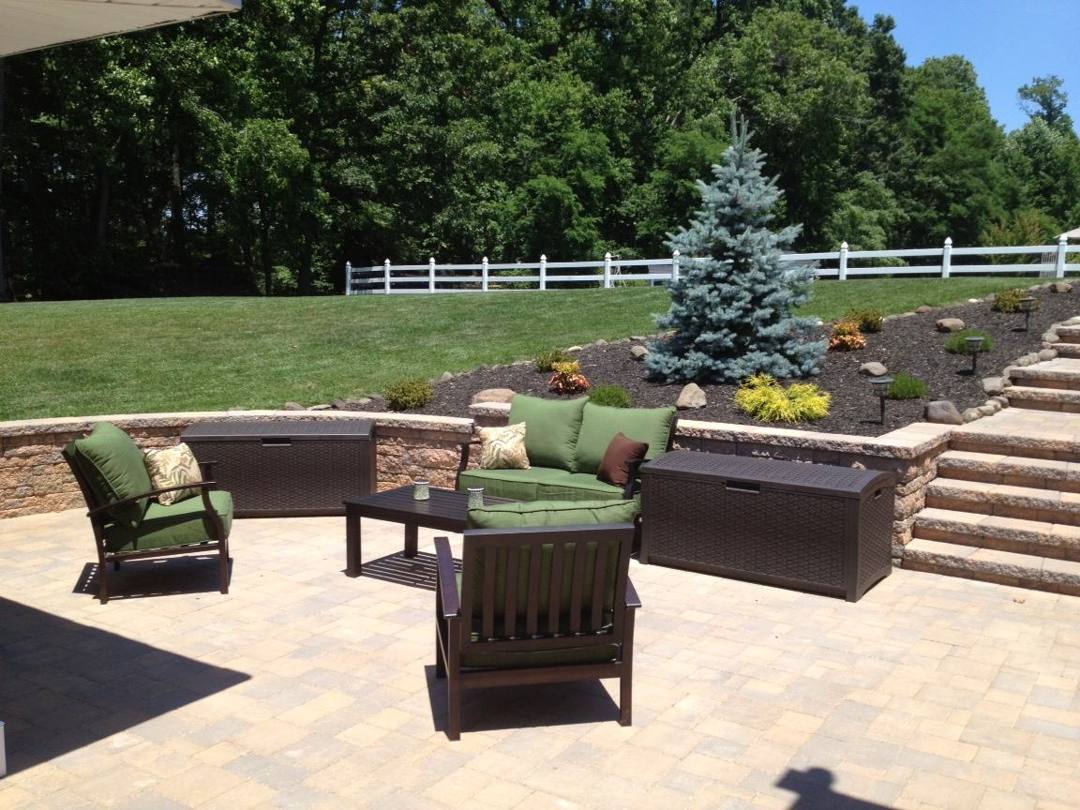 Paver patio with outdoor sofas and a seat wall beside garden steps