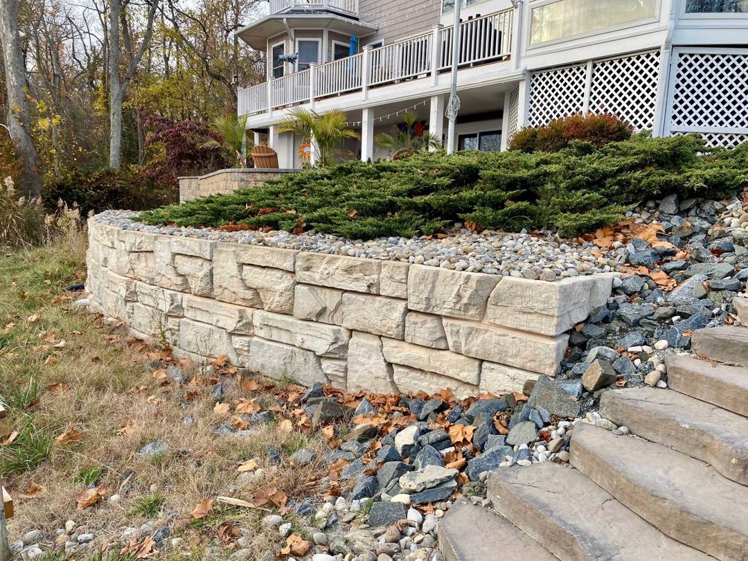 Natural stone retaining wall with stone steps and river rock