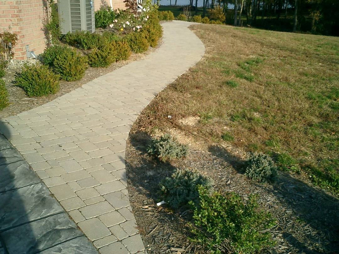 Curving paver walkway alongside a landscaped slope